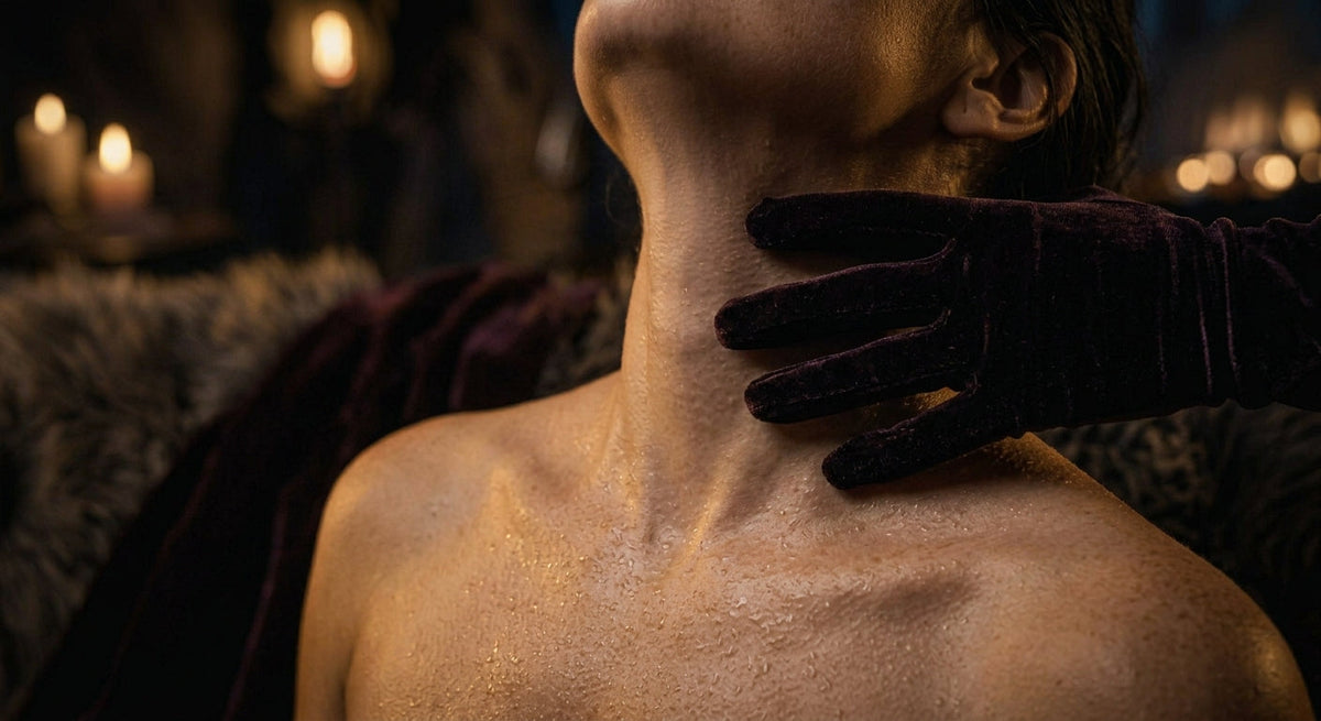 A moody, low-key editorial photo depicting power dynamics and physical surrender through subtle touch and atmospheric shadows.