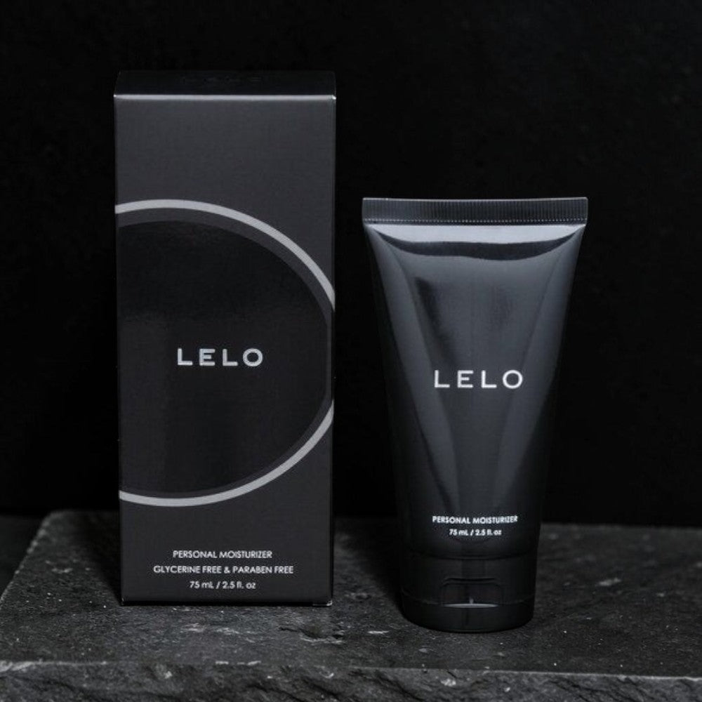 LELO Personal Moisturizer shown with its black retail box and matching squeeze tube on a dark textured surface against a black background.