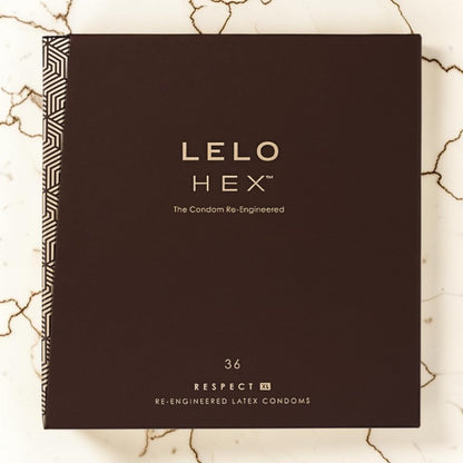 LELO Hex re-engineered latex condoms in a dark brown rectangular box with gold lettering, placed on a light marble surface with natural cracks.