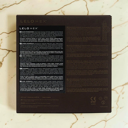The back of a LELOHEx cosmetic box, featuring product information in English and French, photographed flat on a light beige marble surface.