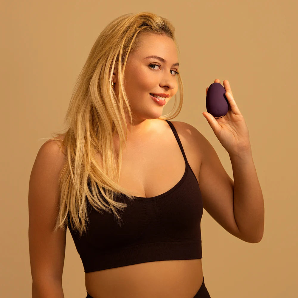 Woman holding a purple egg-shaped object against a beige background