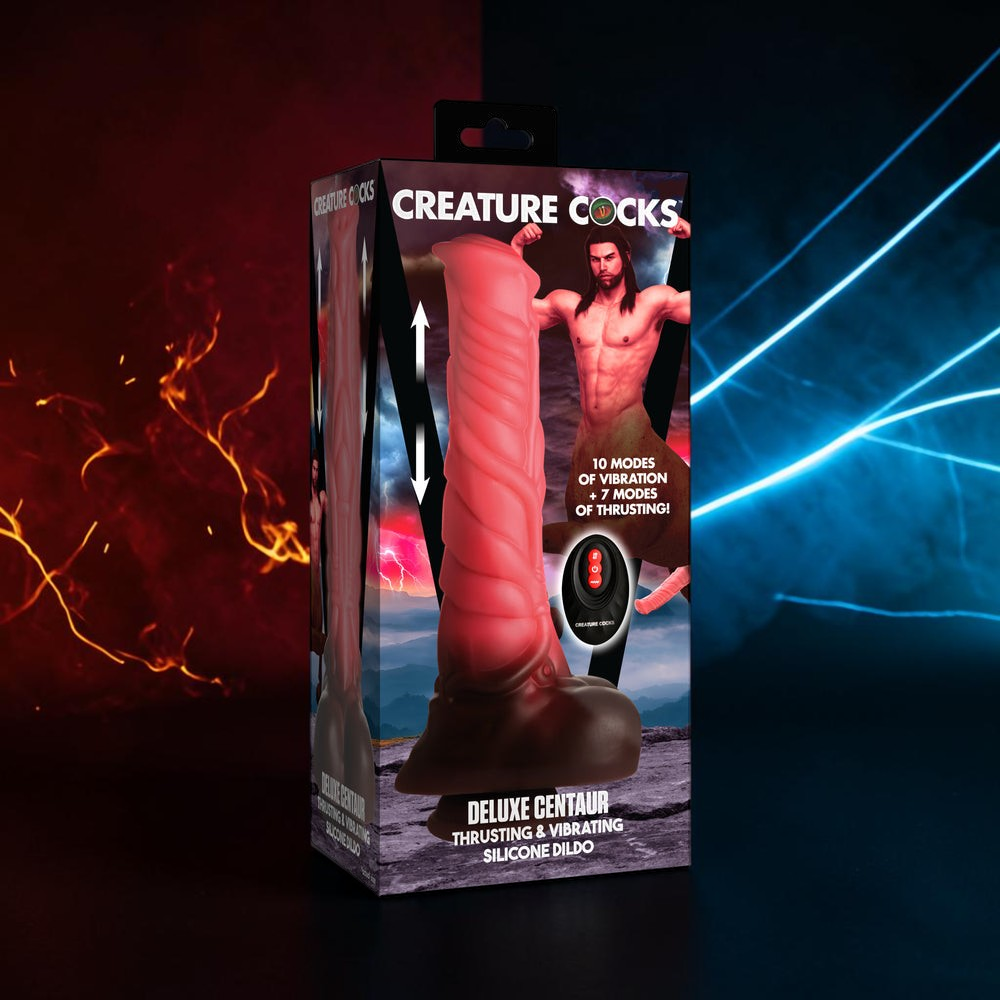 Creature Cocks Deluxe Centurion Thrusting & Vibrating Silicone Dildo in its retail packaging, displayed against a dark background with dramatic red fire on the left and blue light beams on the right.