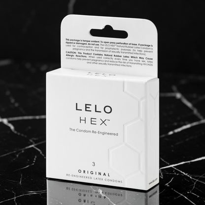 A white box of LELLO HEX Original Re-Engineered Later Condoms on a black marble surface, with the back of the packaging visible above the front.