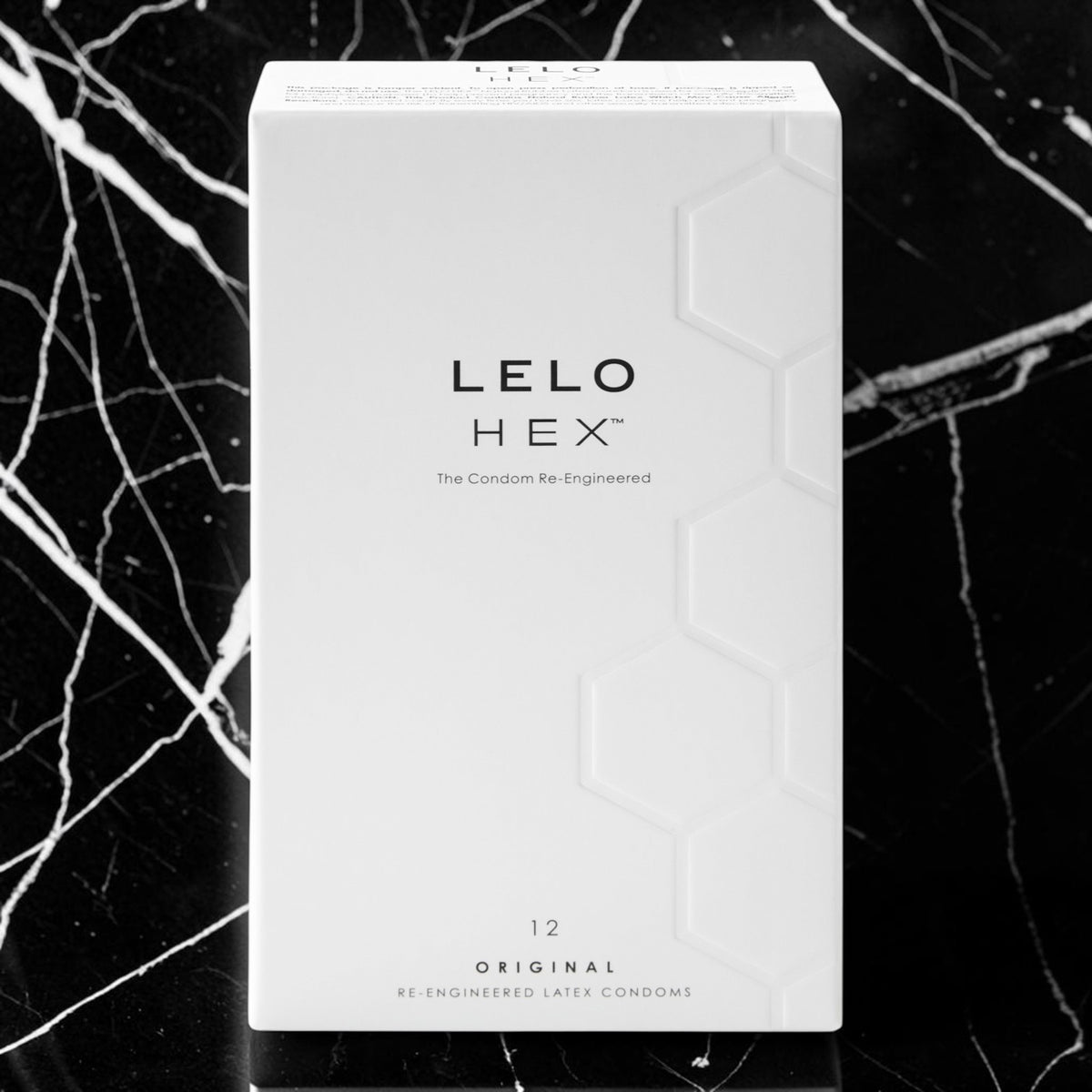 A white rectangular product box for LELO HEX condoms, featuring black text and a subtle hexagonal pattern, set against a black marble background with white veining.