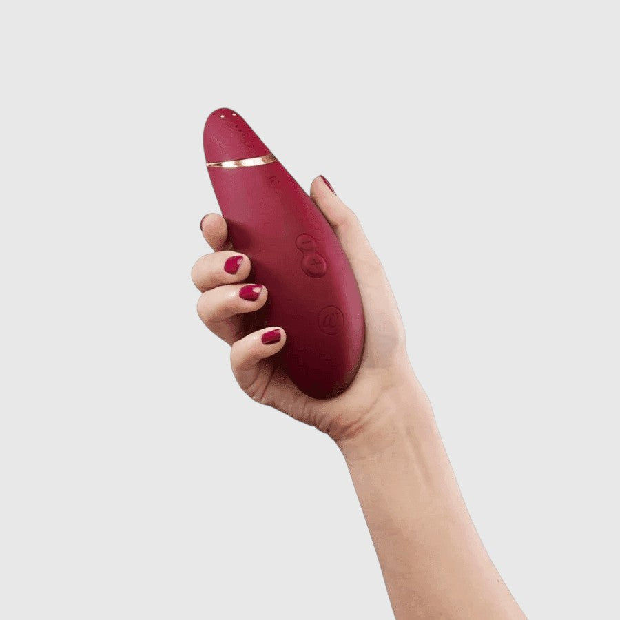 Vibrador de succión Womanizer Premium 2 en color rojo, sostenido en la mano, con tecnología Pleasure Air de PlayLoveToys
