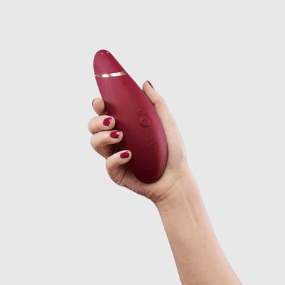 Vibrador de succión Womanizer Premium 2 en color rojo, sostenido en la mano, con tecnología Pleasure Air de PlayLoveToys